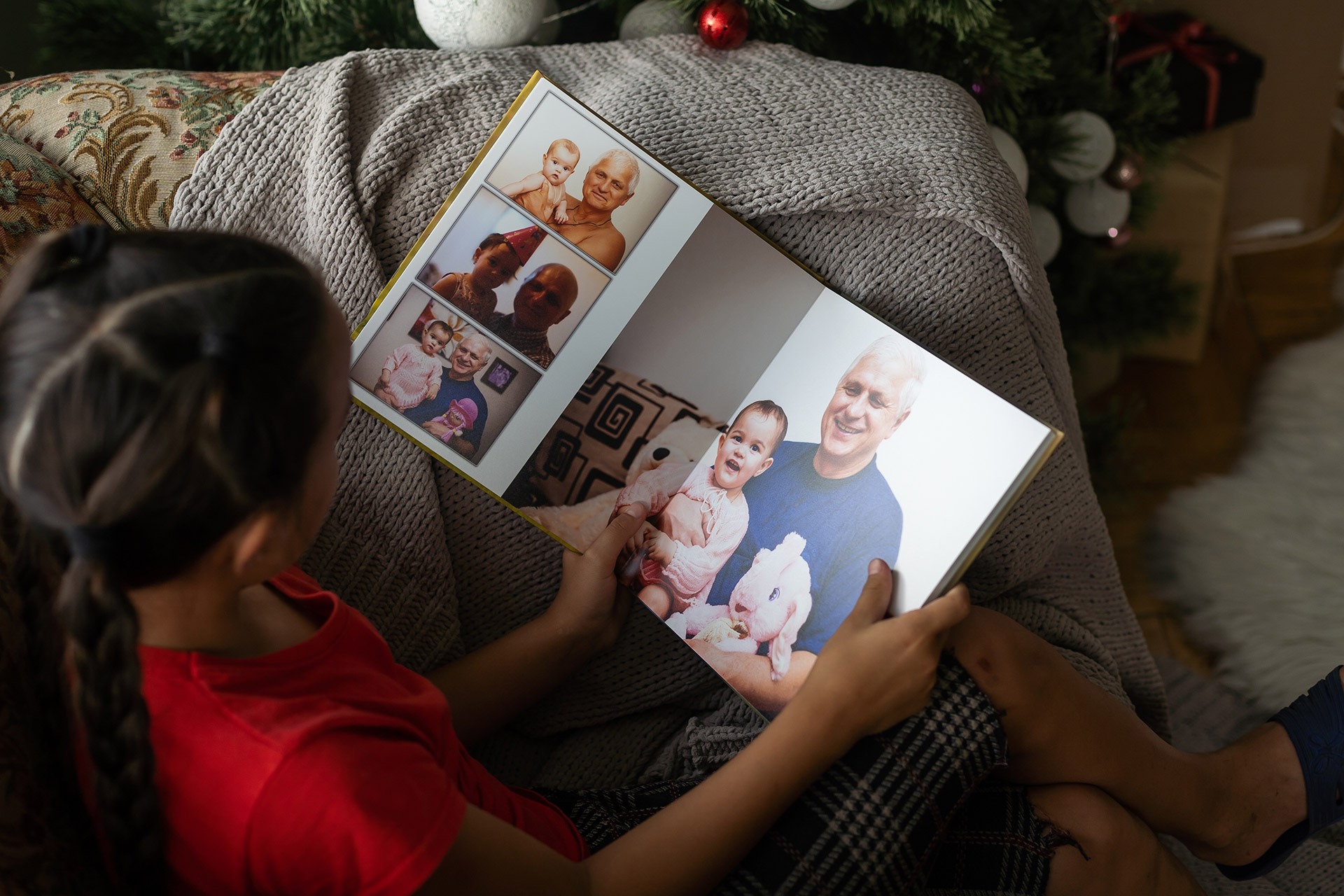 Young girl looking through a custom photo booklet featuring family portraits, an example of booklet printing in Calgary for personal memories.