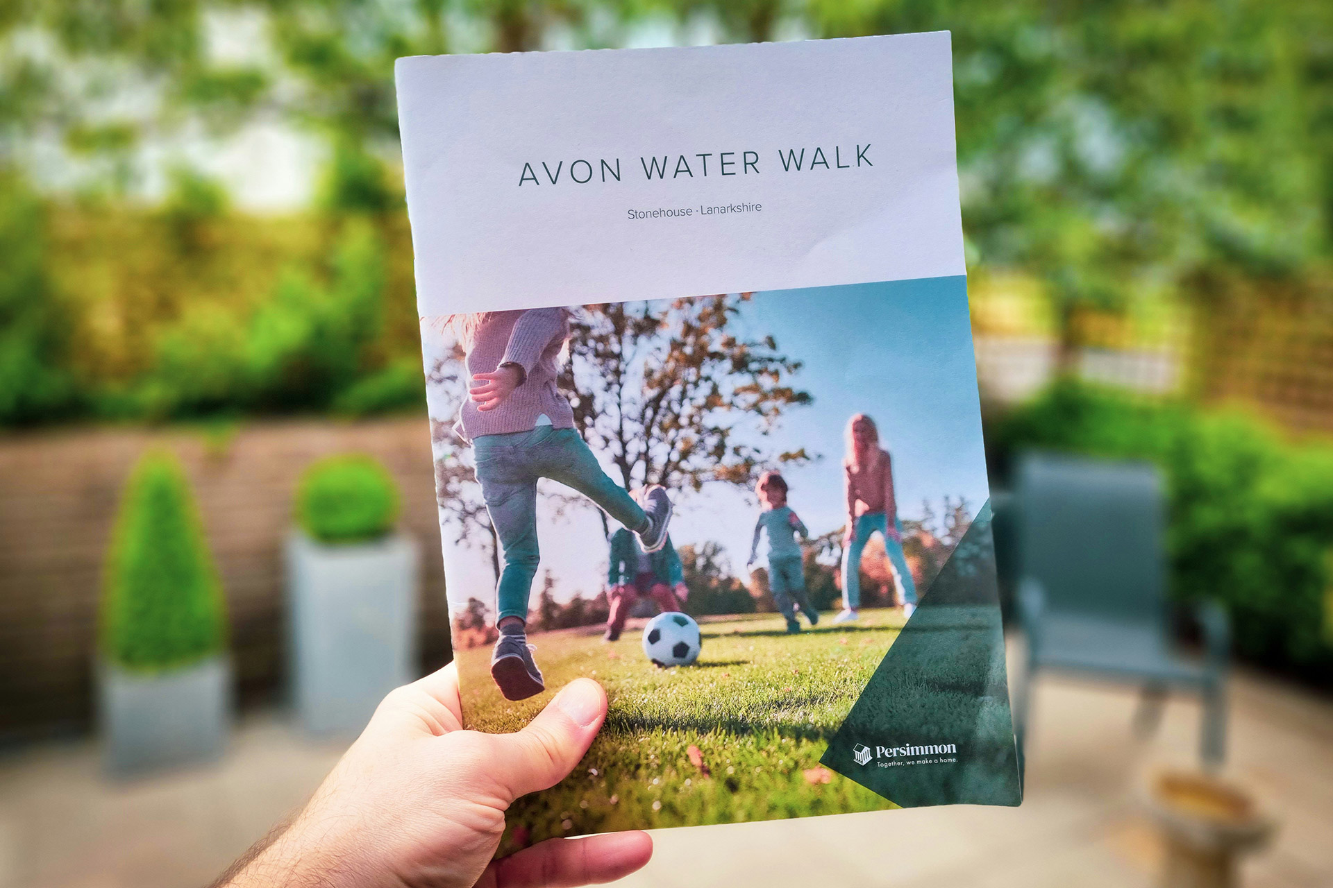 Hand holding a custom brochure with family lifestyle imagery, highlighting brochure printing in Calgary for community and promotional use.