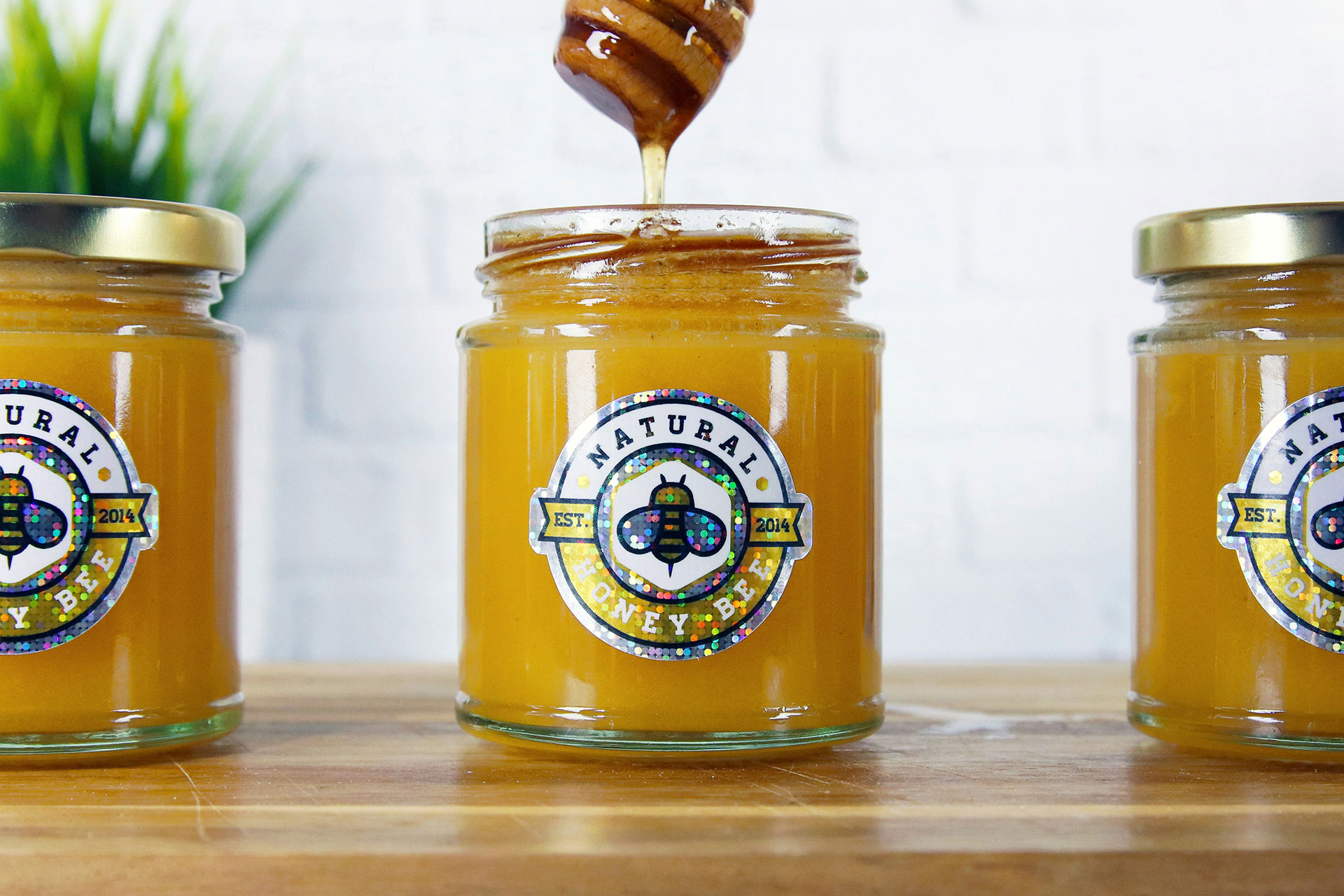 Glass jars of honey with custom holographic labels, an example of sticker printing in Calgary for food and beverage branding.
